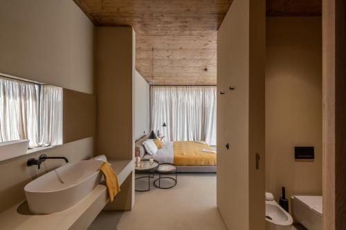 阿尔贝诺阿Herdade da Malhadinha Nova - Relais & Châteaux的带浴缸的浴室和1间带1张床的卧室