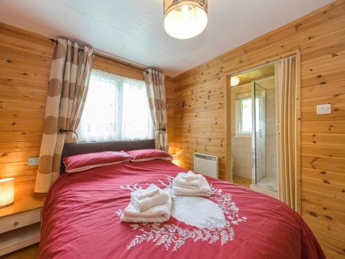 AdfortonThe Log Cabin的一间卧室配有红色的床和毛巾