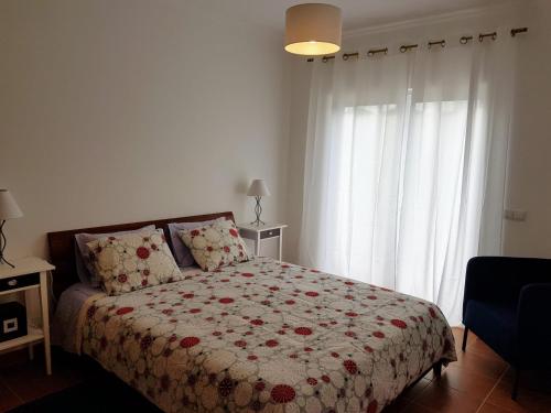 阿尔热祖尔Cozy apartment in Algarve West Coast - Aljezur (2 min da Praia Monte Clérigo)的一间卧室配有一张带鲜花毯子的床和窗户。