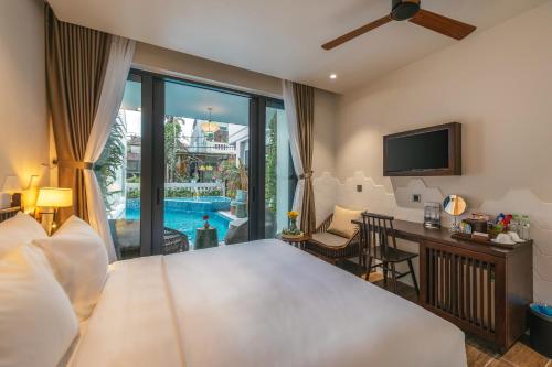 会安Volar de Faifo Villa的酒店客房设有一张床、一张书桌和一台电视机。