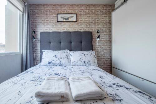 Taytay1BR Interiored Condo with WiFi, Netflix, Hot Shower - The Hive Residences的一间卧室设有一张带砖墙的大床
