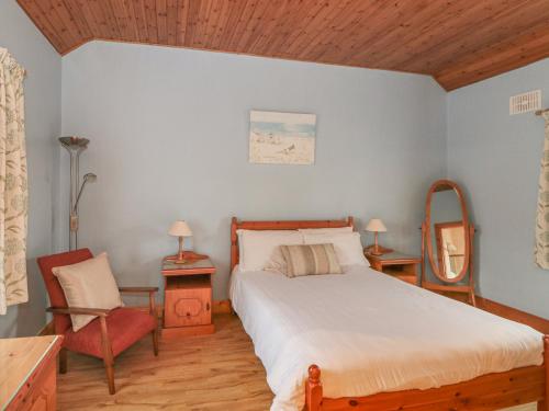 RamsgrangeRose Cottage的一间卧室配有一张床、一把椅子和镜子