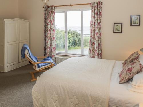 伦维尔Seaspray的一间卧室设有一张床、一个窗口和一把椅子
