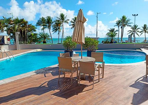 马塞约马塞约玛尔酒店的游泳池旁配有遮阳伞的桌椅