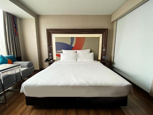 暖武里府曼谷诺富特因帕特酒店的卧室配有一张白色大床和一把椅子
