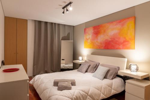 波尔图Porto Dragão的卧室配有白色的床和墙上的绘画作品