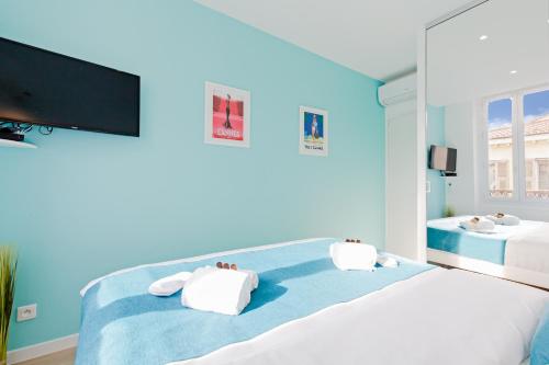 戛纳L'Albion YourHostHelper的一间蓝色卧室,配有两张床和一台平面电视