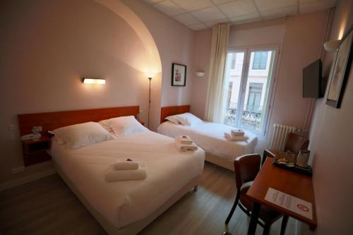 图卢兹威尔逊广场酒店的一间卧室设有两张床、一张桌子和一个窗口。