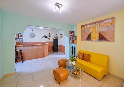 帕莫瑞Peneka Hotel的一间带黄色沙发的客厅和一间候机室