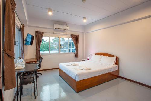 南邦Kanyanat Boutique Hotel的一间卧室配有一张床、一张桌子和一个窗户。