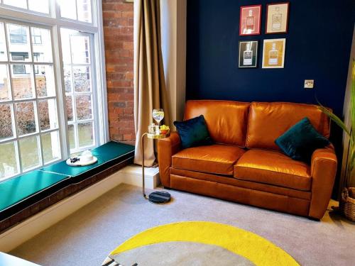 约克Cocoa Lily - River fronted studio with secure parking的客厅设有棕色的沙发和窗户。