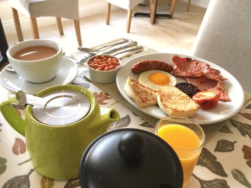 基尔基尔Mourne Country House Bed and Breakfast的一张早餐桌,包括一盘鸡蛋培根和咖啡