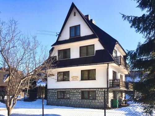 波罗宁U Wiesi的雪上有黑色屋顶的大型白色房屋