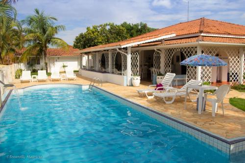圣代佩德罗Recanto Serenissima的房屋旁的游泳池配有椅子和遮阳伞