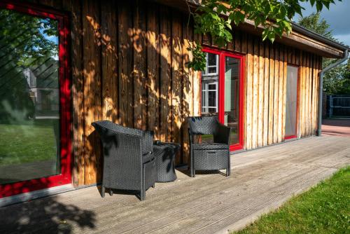利耶帕亚Altribute Studio w Sauna Secure Parking wifi 90mbs的一个带两把椅子的木制甲板和一座建筑