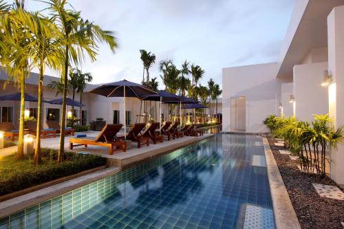 卡塔海滩BLU PINE Villa & Pool Access - SHA Plus的度假酒店的游泳池配有椅子和遮阳伞