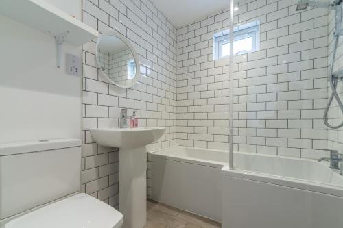 以撒港Miss Fishers的白色的浴室设有水槽和浴缸。