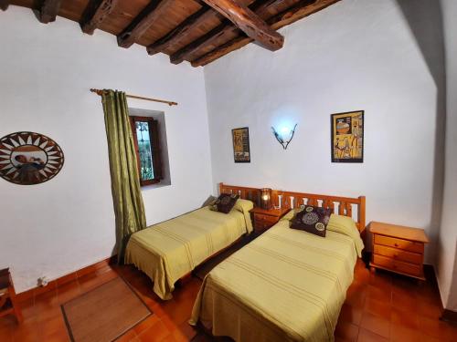 圣胡安包蒂斯塔Can Joan Yern的配有白色墙壁和木地板的客房内的两张床