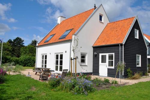 迪斯胡克DE DUINDISTEL Bed by the Sea的黑色和白色的房子,有橙色的屋顶