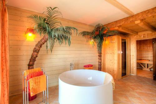 博登斯多夫Mathiasl Wellness-Ferienhäuser的带浴缸和棕榈树的浴室