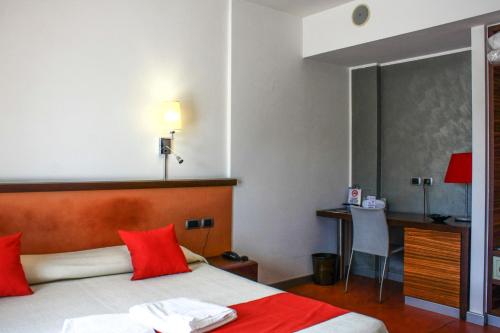 圣焦万尼泰亚蒂诺贝德商务酒店的一间卧室配有一张带红色枕头的床和一张书桌