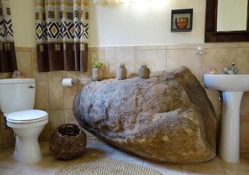 姆巴巴内Vekis Village的浴室的角落设有一个大型岩石形浴缸