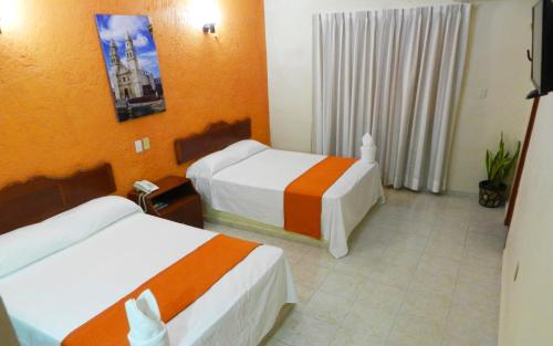 坎佩切乌可苏尔卡旅馆的酒店客房,设有两张带橙色墙壁的床
