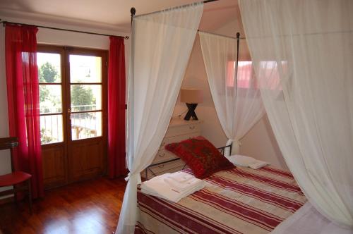 科尔托纳爱丽丝科尔图纳别墅的一间卧室配有一张带红色窗帘的天蓬床