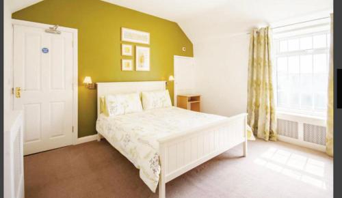 切斯特菲尔德Whitton Lodge B&B的卧室配有白色的床和绿色的墙壁
