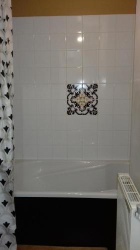特鲁瓦Duplex La Maisonnette 2 Chambres - parking gratuit的浴室设有白色浴缸和瓷砖墙。