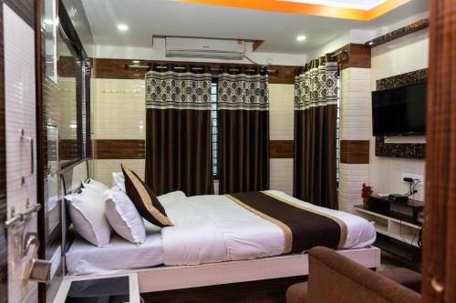 西里古里Tirupati Lodge NJP的一间卧室配有一张床和一台电视。
