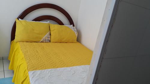 伊列乌斯Suíte zona Sul de ilhéus próximo a praia的一张带黄色和白色枕头的床