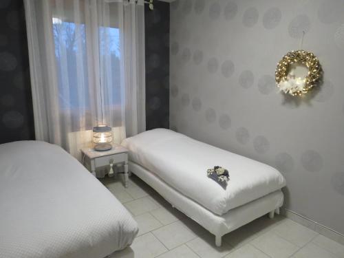 ManthelonChambre d'hôtes La Clé du Bonheur的一间卧室设有两张床,墙上有花圈