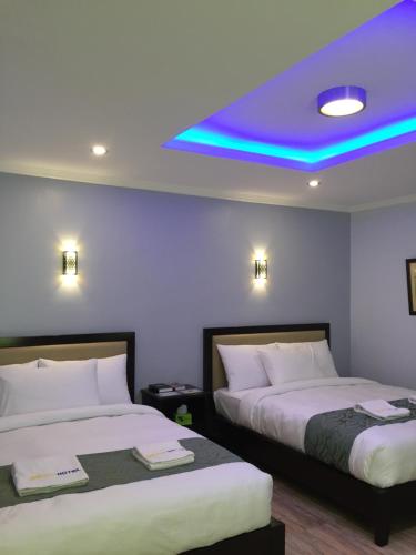 卡瓦延市MAISON HOTEL的紫色天花板的酒店客房内的两张床