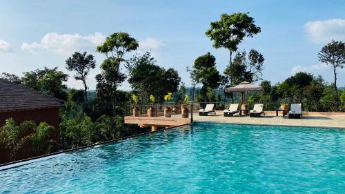 瑟格莱什布尔Machaan Plantation Resort, Sakleshpur的一个带甲板和椅子的游泳池以及树木