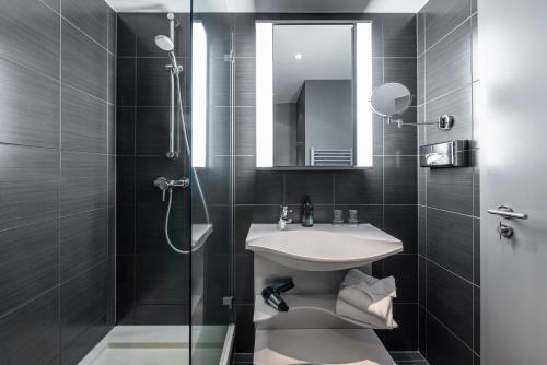 柏林柏林选帝侯大街阿德吉奥公寓式酒店的浴室配有盥洗盆和带镜子的淋浴