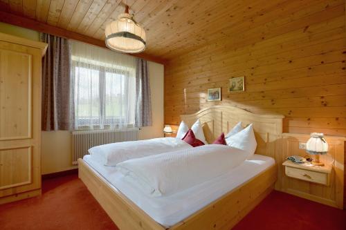 瑟尔Bauernhof Strasserhof的卧室配有一张白色大床和木墙