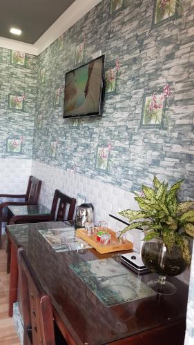 潘郎Khách sạn Ánh Đông的一间设有桌子的房间和墙上的电视