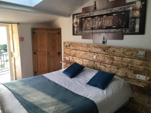 瓦劳里埃Logis Le Mas de Valaurie的一间卧室配有一张带木制床头板的床