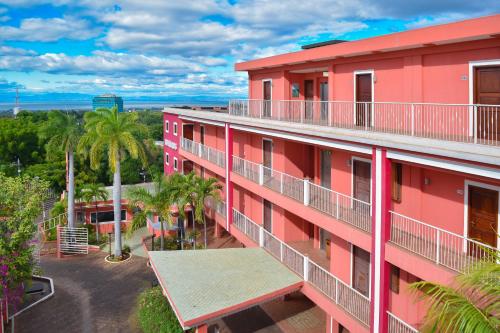 马那瓜RDG酒店的享有棕榈树粉红色建筑的空中景致