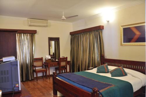 钦奈Niketana @ Boat Club的一间酒店客房,一间设有一张床和一张书桌