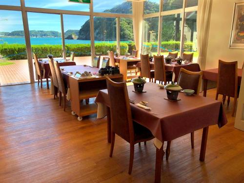 胜浦市那吉西亚酒店的餐厅设有桌椅和大窗户。