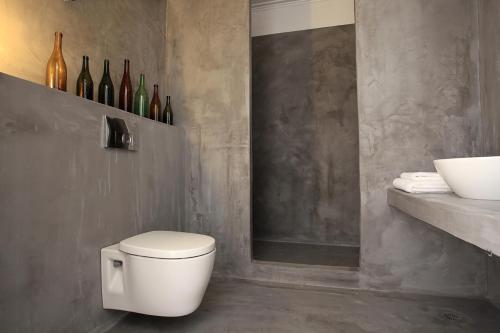 锡米Limani Life的浴室设有卫生间和带葡萄酒瓶的架子。