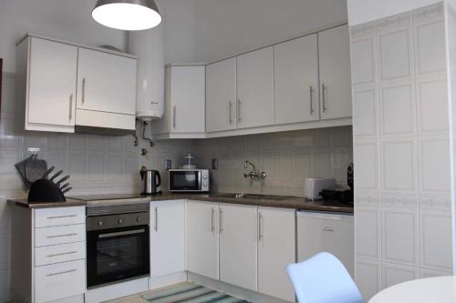 大里贝拉Margarida House - Stone Apartment的白色的厨房配有白色的橱柜和微波炉