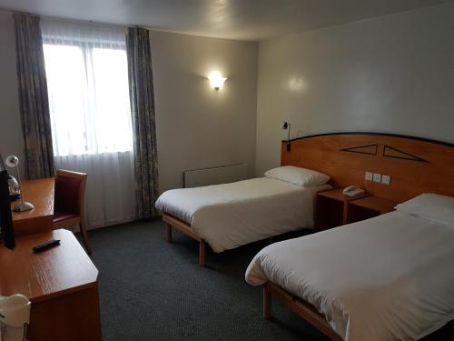 卡迪夫宜必思加迪夫门-国际商业园酒店的酒店客房设有两张床和窗户。