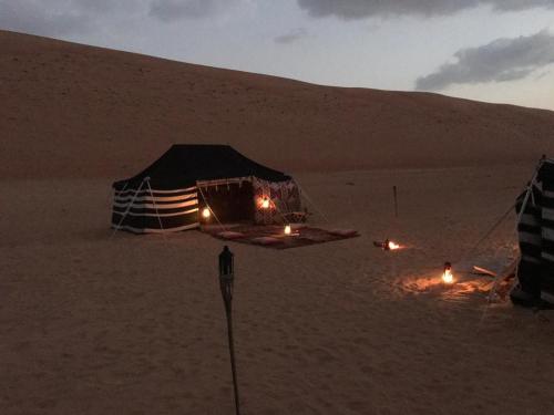 BadīyahSultan Private Desert Camp的沙漠中的帐篷,沙子上灯火通明
