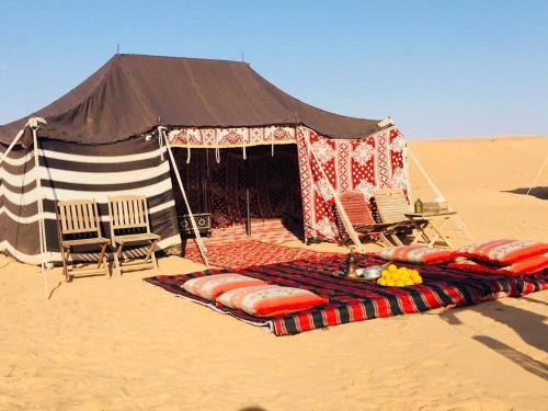 BadīyahSultan Private Desert Camp的沙漠中带椅子的帐篷