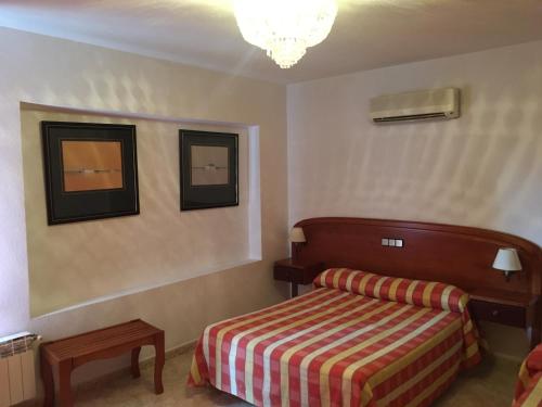 索托德尔雷亚尔阿萨德索托大旅馆 的卧室配有一张床,墙上挂有两张照片