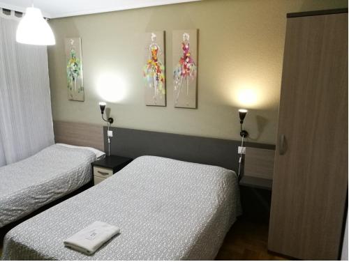 布尔戈斯圣地亚哥旅馆的酒店客房设有两张床,墙上挂有绘画作品