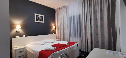 Afumaţi克里斯蒂安酒店的一间卧室配有一张带红色和白色毛巾的床